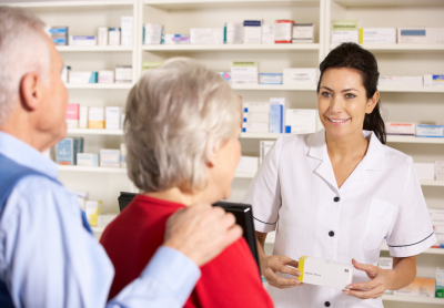 pharmacist dispensing to senior couple smiling