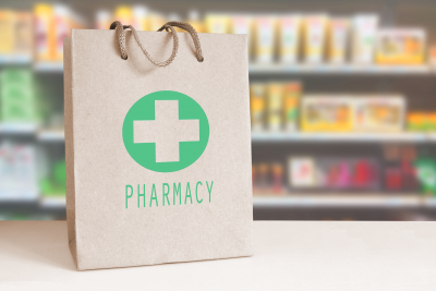 Recycled paper bag with a green Pharmacy logo in a drugstore.